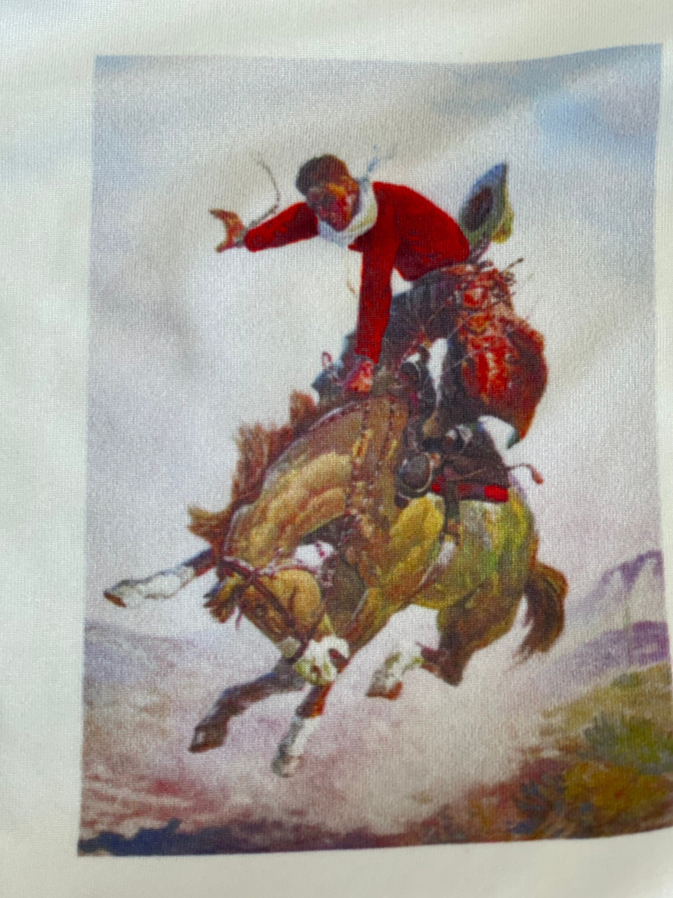 CLOSE UP VIEW OF TSHIRT GRAPHIC FETURING A COWBOY TRYING TO STAY ON BOARD HIS BRONCY HORSE! WILL HE DO IT? Top is white with a SORREL PAINT bucking horse and cowboy centered on t-shirt. cowboy IS WEARING A RED SHIRT AND RED CHAPS WITH A WHITE BANDANA AND IT LOOKS LIKE HE'S ABOUT TO LOSE HIS HAT! 