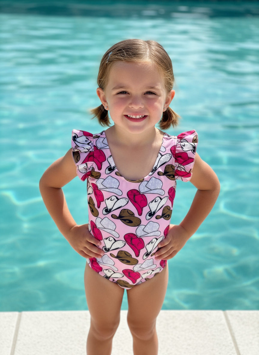 Cowgirl Swimsuit | Pink Cowgirl Hat Swimsuit | Western Swimsuits Girls, Sweetheart of the Rodeo

The cutest Cowgirl Swimsuit is here! Featuring hot pink, silver, and brown cowgirl hats on a bubblegum pink background, this one-piece swimsuit is a must-have for little rodeo queens. The flutter neckline adds the perfect touch of sweetness, making it as adorable as it is stylish!
Ships FREE FROM MONTANA with any $35+ purchase!
