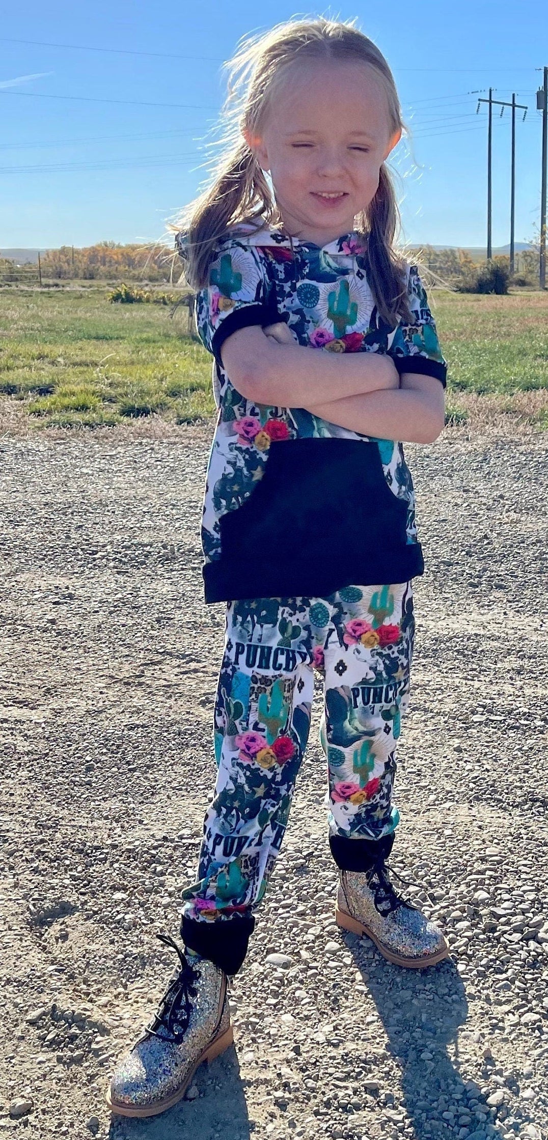 Girls Cowgirl Outfit | Western Hoodie Jogger Set for Kids  This Girls PUNCHY Cowgirl Outfit is full of retro cowboy vibes. This Western outfit features an allover Western print with matching jogger pants and a lightweight, short-sleeved hoodie top.