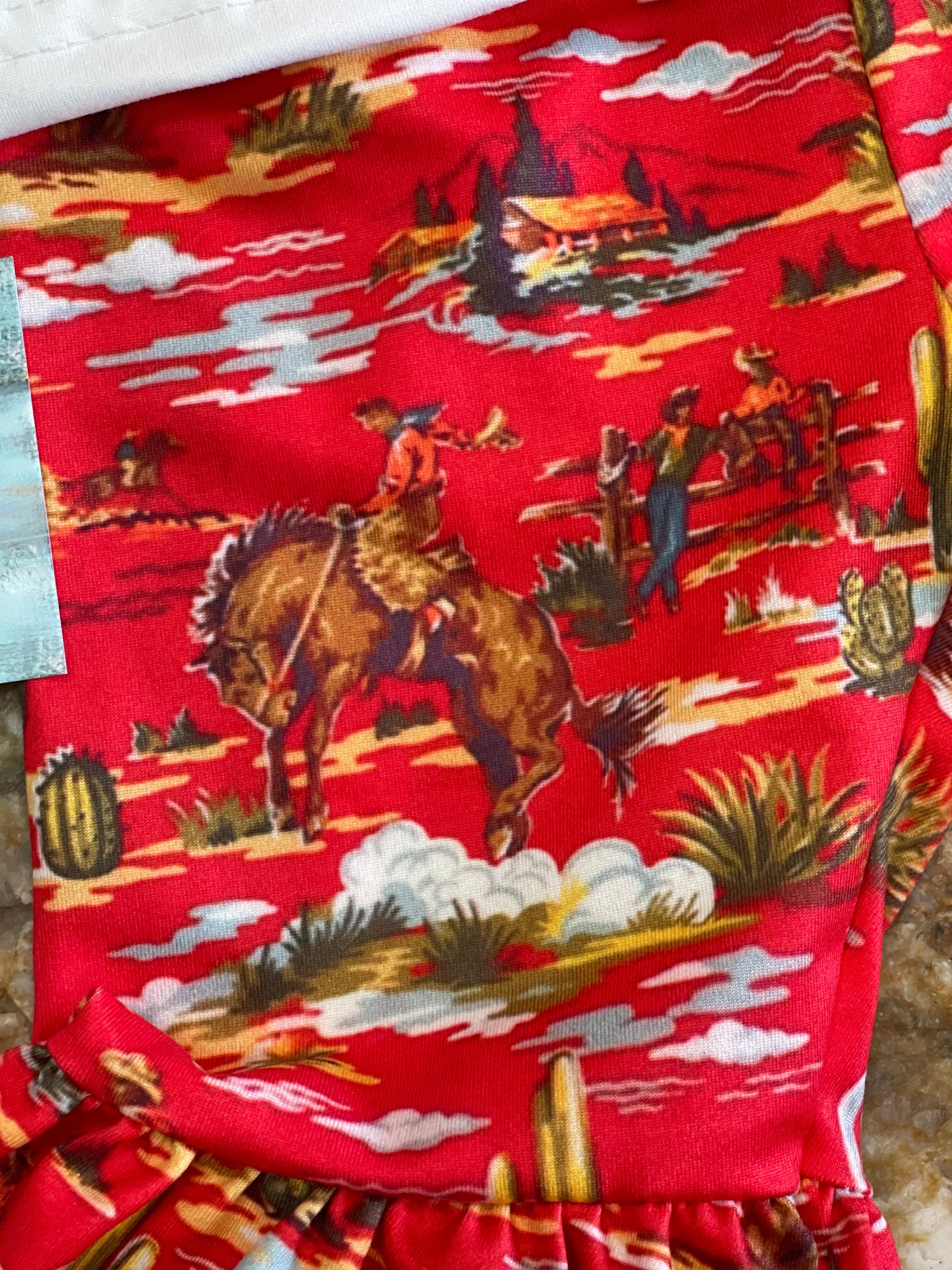 CLOSE UP VIEW OF THE RED BELL BOTTOM PANTS SO YOU CAN SEE THE VINTAGE COWBOY PRINT FABRIC, BUCKING HORSES, CACTI, AND ALL THE SPLENDID COWBOY DETAIL OF THESE WESTERN FLARE PANTS! 
