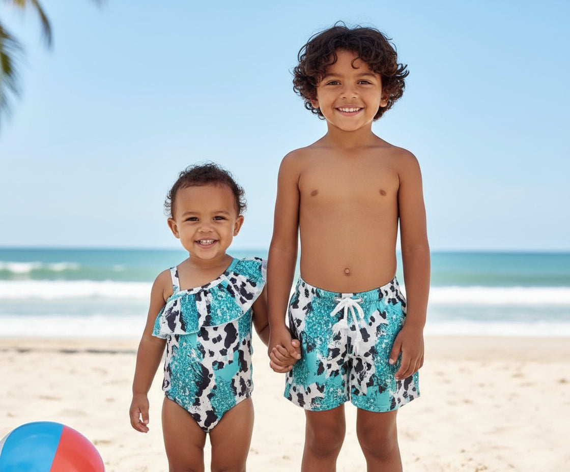 Turquoise Cowprint Matching Sibling Swimsuits – Western Swimwear for Kids

Make a splash in these adorable turquoise, black, and white cowprint swimsuits! Featuring a ruffled neckline on the one-piece and comfy unlined trunks, this matching set is perfect for little cowboys and cowgirls. Available in sizes 0-3 months to 8/9, these versatile swimsuits are designed for summer fun, whether at the pool, beach, or backyard adventures. Ships FREEwith $35+ purchase from MONTANA.