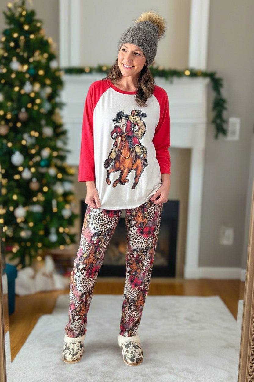 family cowboy Santa Christmas pajamas feature a raglan-style top with Santa riding his best horse, carrying a sack of packages. The top has red sleeves and neckline. The bottoms have an all-over cheetah print, buffalo plaid and Santa on his horse