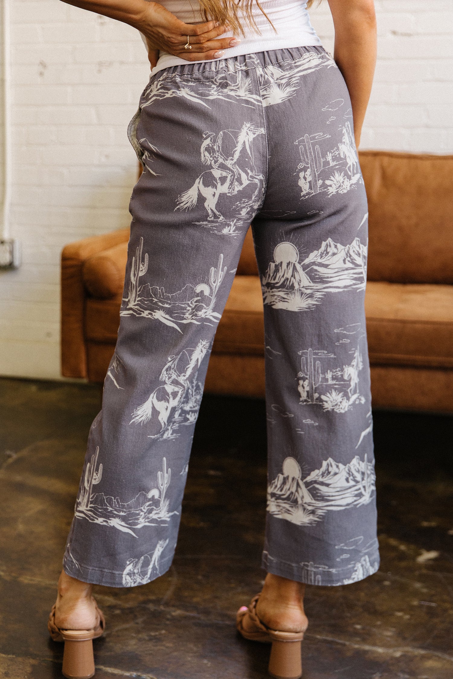 Person wearing gray pants with white cowboy desert patterns in a casual setting.