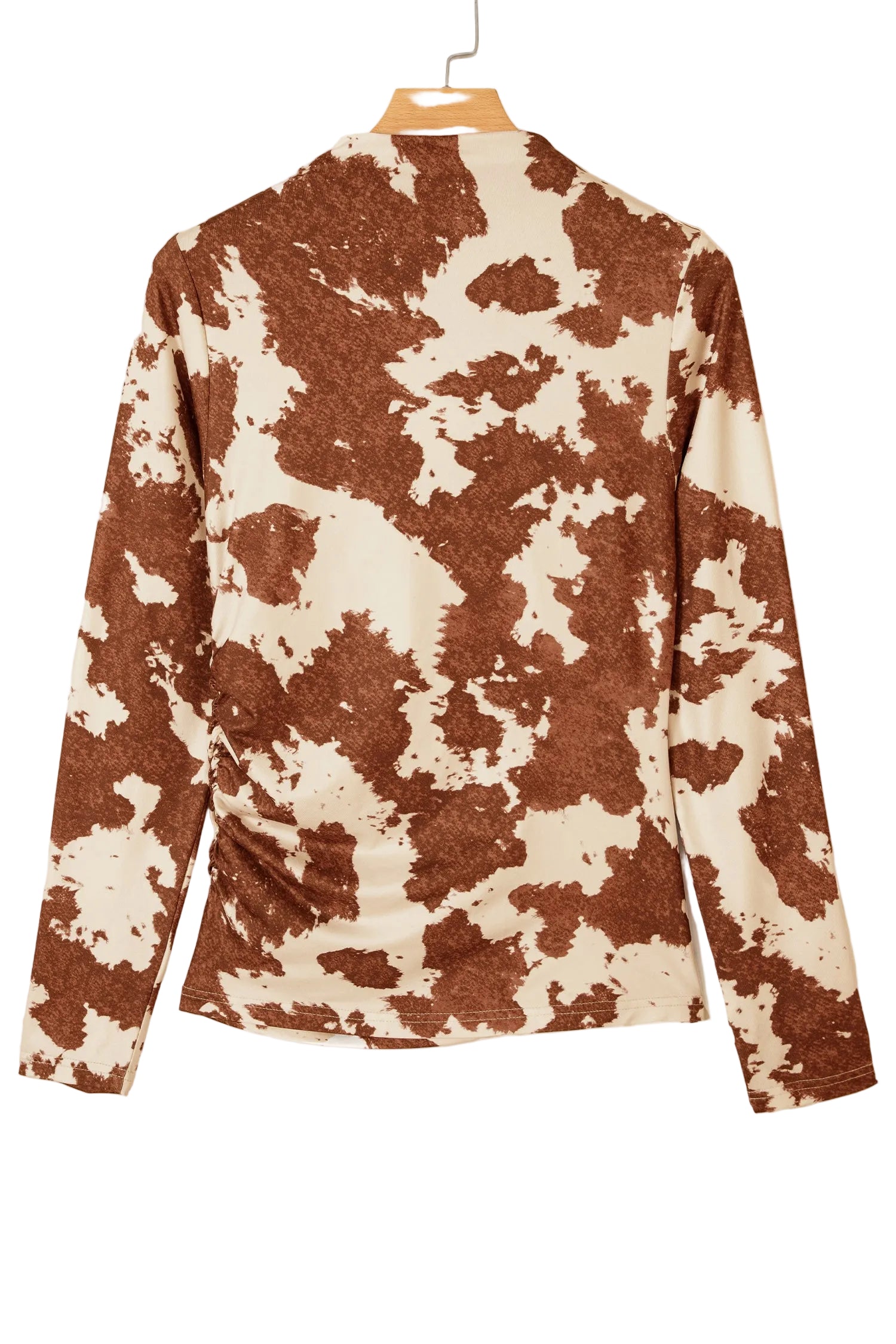 A long-sleeve top with a brown and cream cow-print pattern, hanging on a wooden hanger against a plain off-white background.