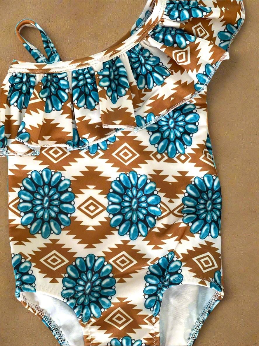 Cowgirl Swimsuit, Turquoise Conchos, Western Swimsuits, SOUTHWESTERN, Squash blossoms, Girls One piece swim, Ruffle Swimsuit, Girls' Western Swimsuit  Two of our favorite things – Aztec prints and turquoise concho squash blossoms – come together in this stunning Western-inspired swimsuit! 😍 This girls' one-piece ruffle swimsuit is a must-have for little cowgirls who love bold, Southwestern style. Available 0-3 months - girls 12/14. Ships FREE $35+ order from Montana.