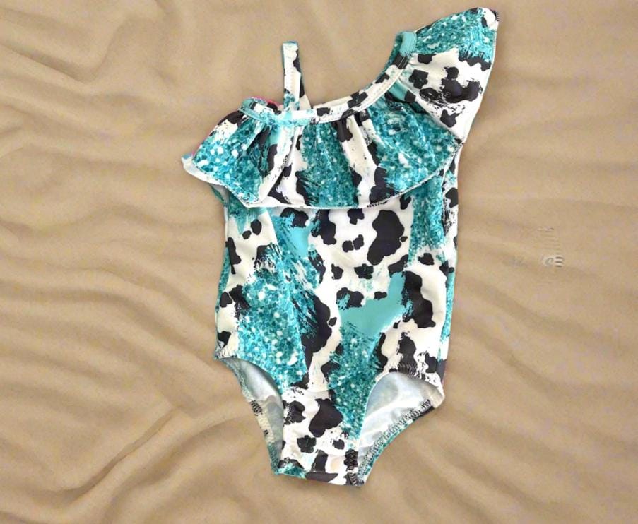 Turquoise Cowprint Matching Sibling Swimsuits – Western Swimwear for Kids

Make a splash in these adorable turquoise, black, and white cowprint swimsuits! Featuring a ruffled neckline on the one-piece and comfy unlined trunks, this matching set is perfect for little cowboys and cowgirls. Available in sizes 0-3 months to 8/9, these versatile swimsuits are designed for summer fun, whether at the pool, beach, or backyard adventures. Ships FREEwith $35+ purchase from MONTANA.