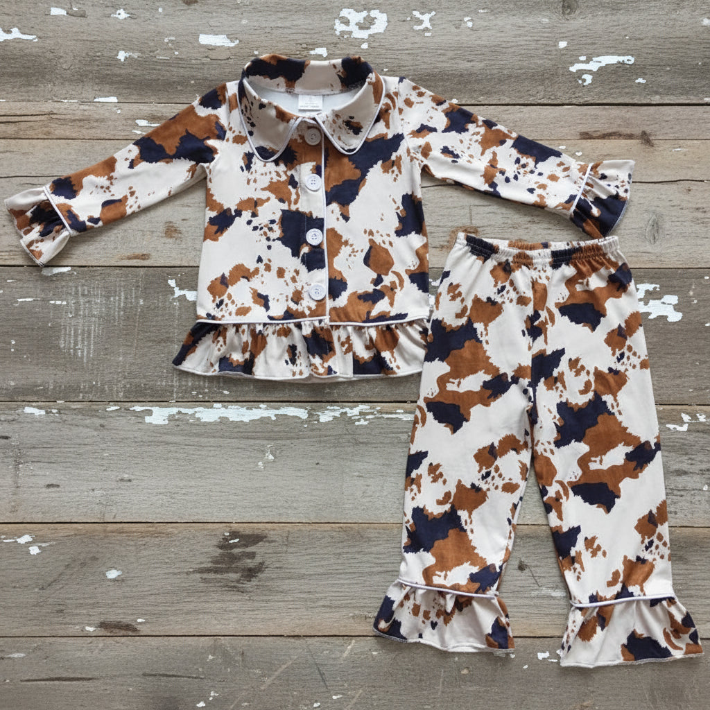 girls Cow print shirt and pants set on a textured surface