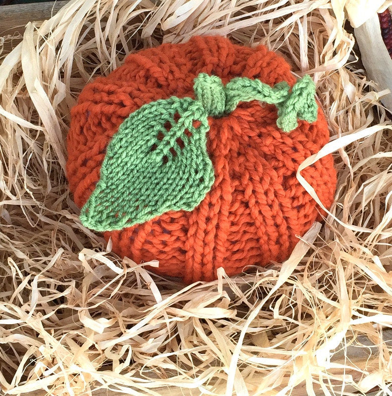 handknit large pumpkin with knit ribs along side, and a handknit leaf and vine sprouting from top! Cute!