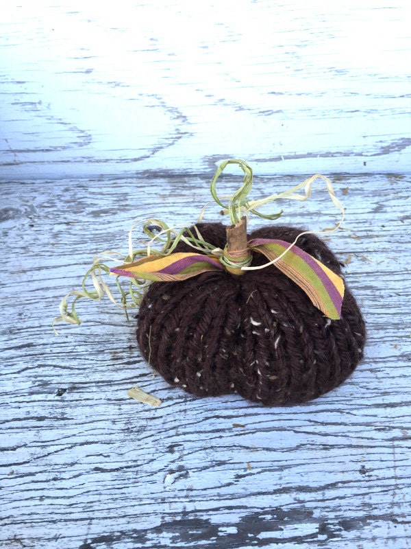 brown hand-knit pumpkin decoration. Pumpkins have sticks, raffia and fabric leaves, and vines.