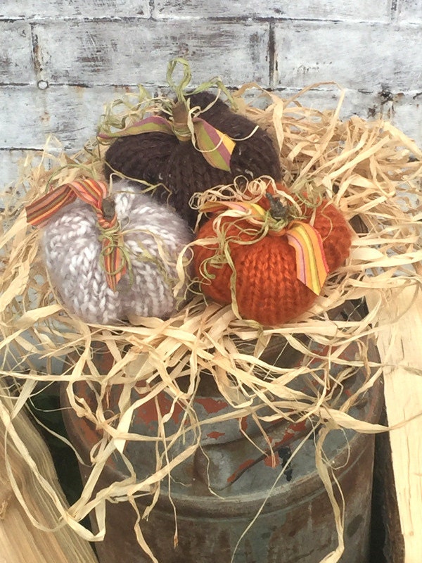 picture of 3 hand knit pumpkins in brown, oatmeal andpumpkin. Pumpkins have stick and fabric leaves and vines.