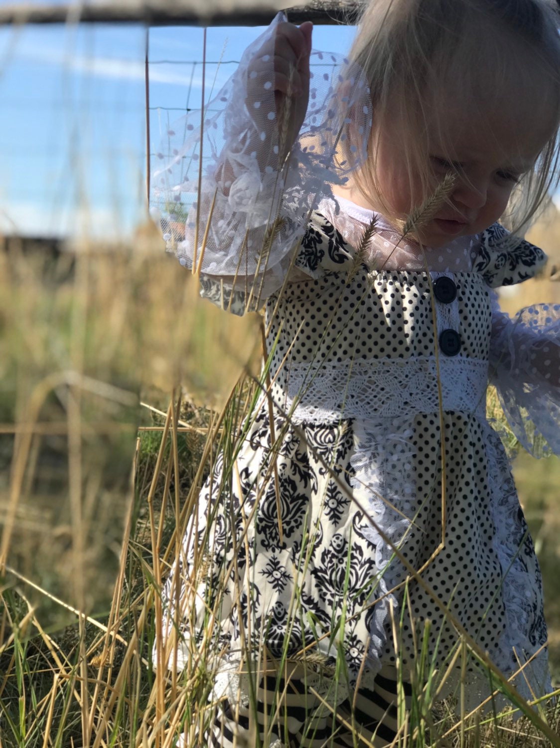 This 3-piece dressy lace outfit for girls includes a lace ruffle top, tunic tank with ruffle straps and buttons, and lace pants with an elastic waist and ruffle ankle details. Outfit is a vintage-inspired black and white design.