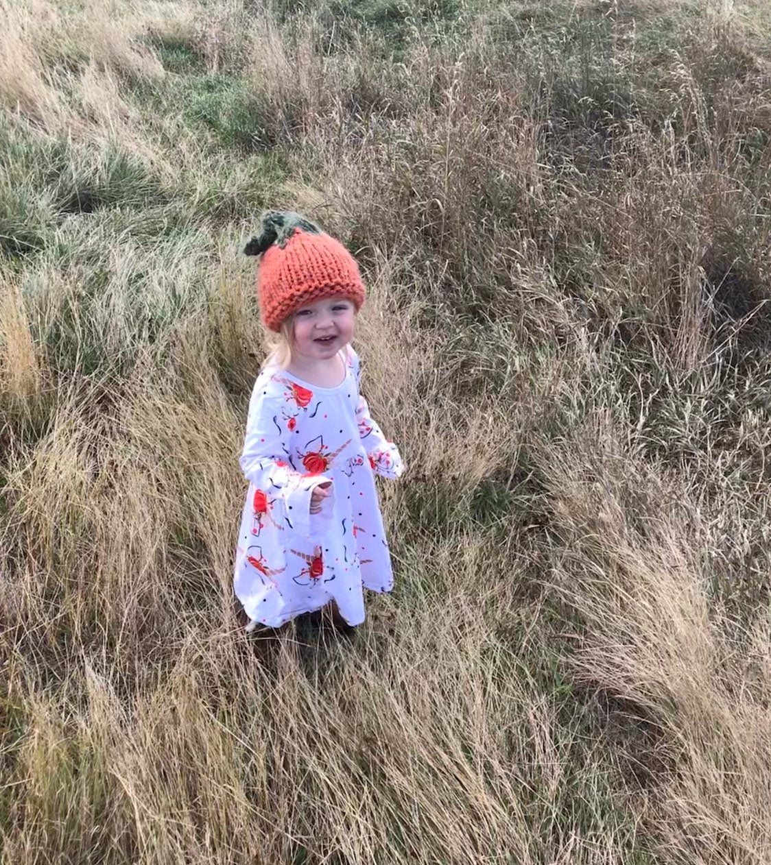 Jernie modeling her handknit pumpkin hat and wearing her Razels pumpkin unicorn dress!