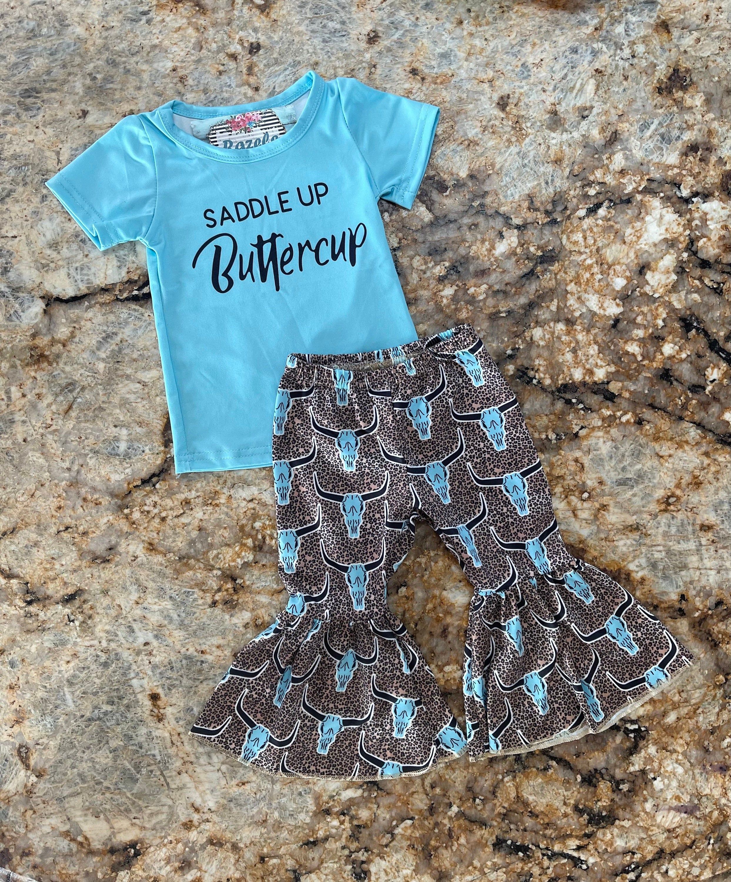 Saddle Up Buttercup! Girls Bell Bottom Outfit, Cowgirl Outfit, Turquoise T-Shirt & Cow Skull Cheetah Print Flares. Featuring a vibrant turquoise t-shirt and flared cow skull cheetah print bell bottoms - a showstopper for any Western-loving girl.