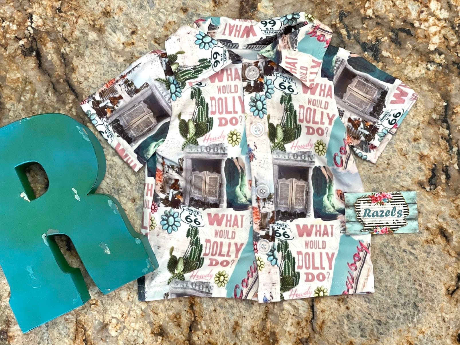 Get ready to dazzle with our adorable What Would Dolly Do? Cowgirl Shirt & Fringe Bodysuit. 
 The button-up shirt features a bold Western-inspired design, while the fringe bodysuit adds flair in vibrant pink. Shop Razels for Girls Western Wear