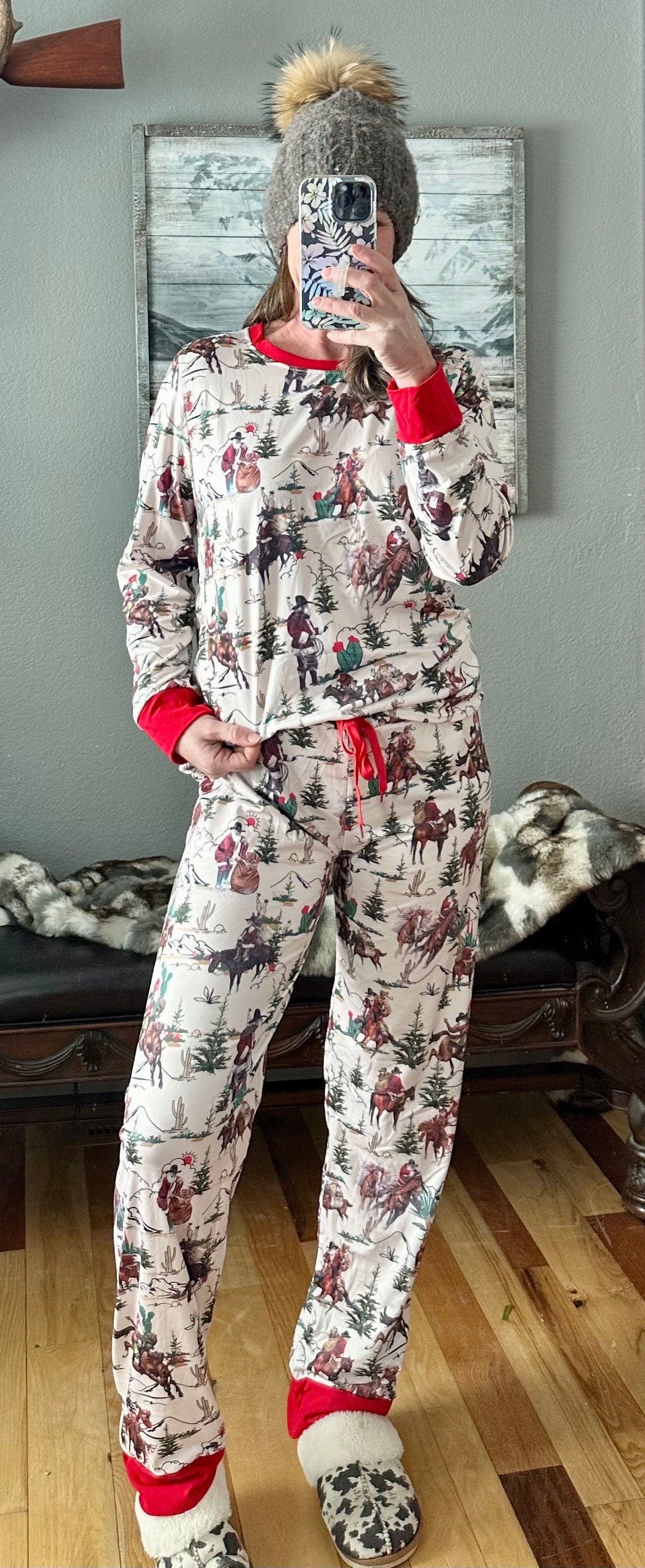 Cowboy Santa Christmas pajamas feature Cowboy Santa delivering packages on his trusty horse, riding among the trees and mountains. The cuffs of the long-sleeve top and pajama pants, as well as the neckline, are red.