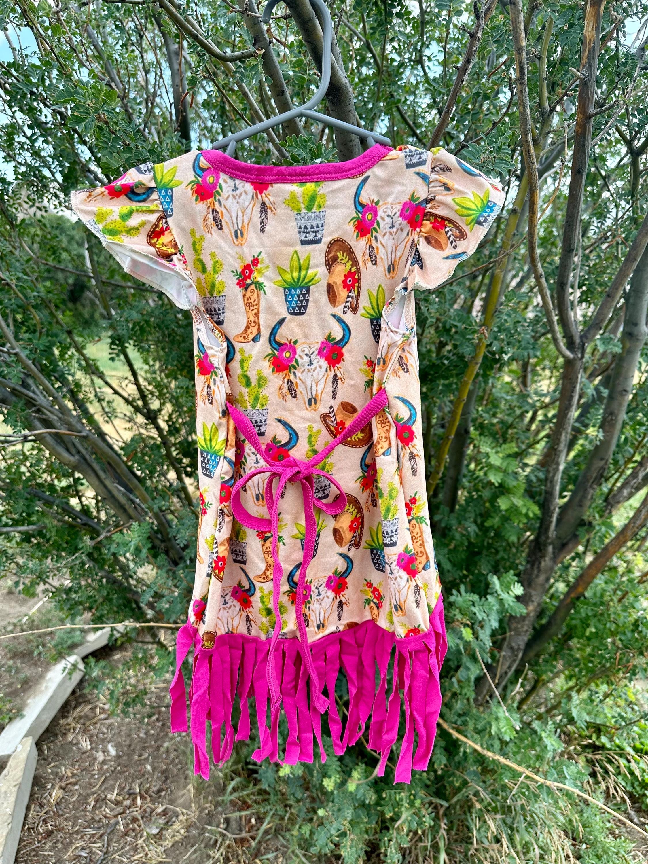 Cowgirl Fringe Dress – The Perfect Western Tunic for Little Cowgirls features a vibrant western print, flutter sleeves, a charming tie-back, and thick pink fringe. Let your little cowgirl shine in this Cowgirl Fringe Tunic Dress!