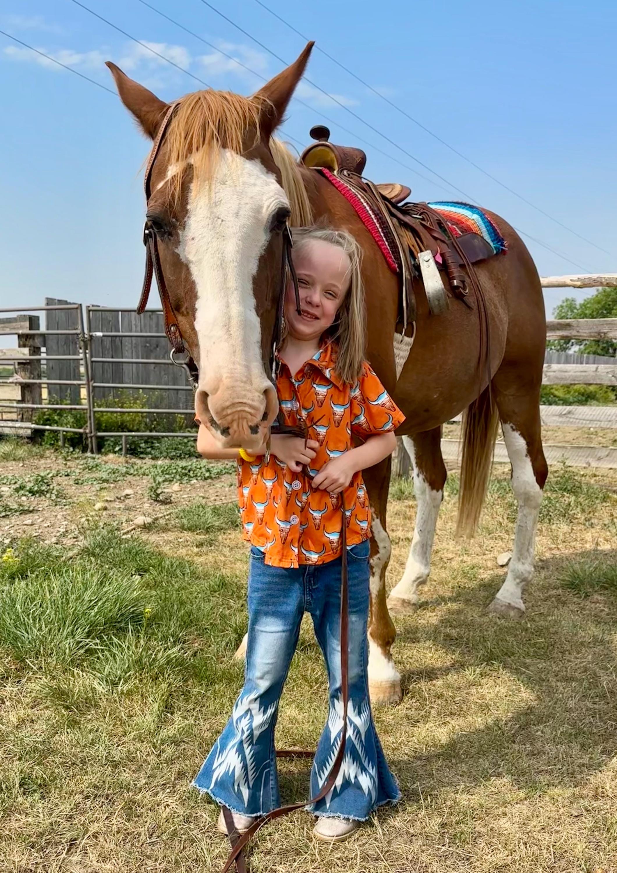 Check out this fun Kids Western button-up shirt featuring a unique desert highway scene inside steer heads. In a bold orange, this cowboy shirt perfectly blends cool and classic Western style—a shirt any cowkid would love! 🧡