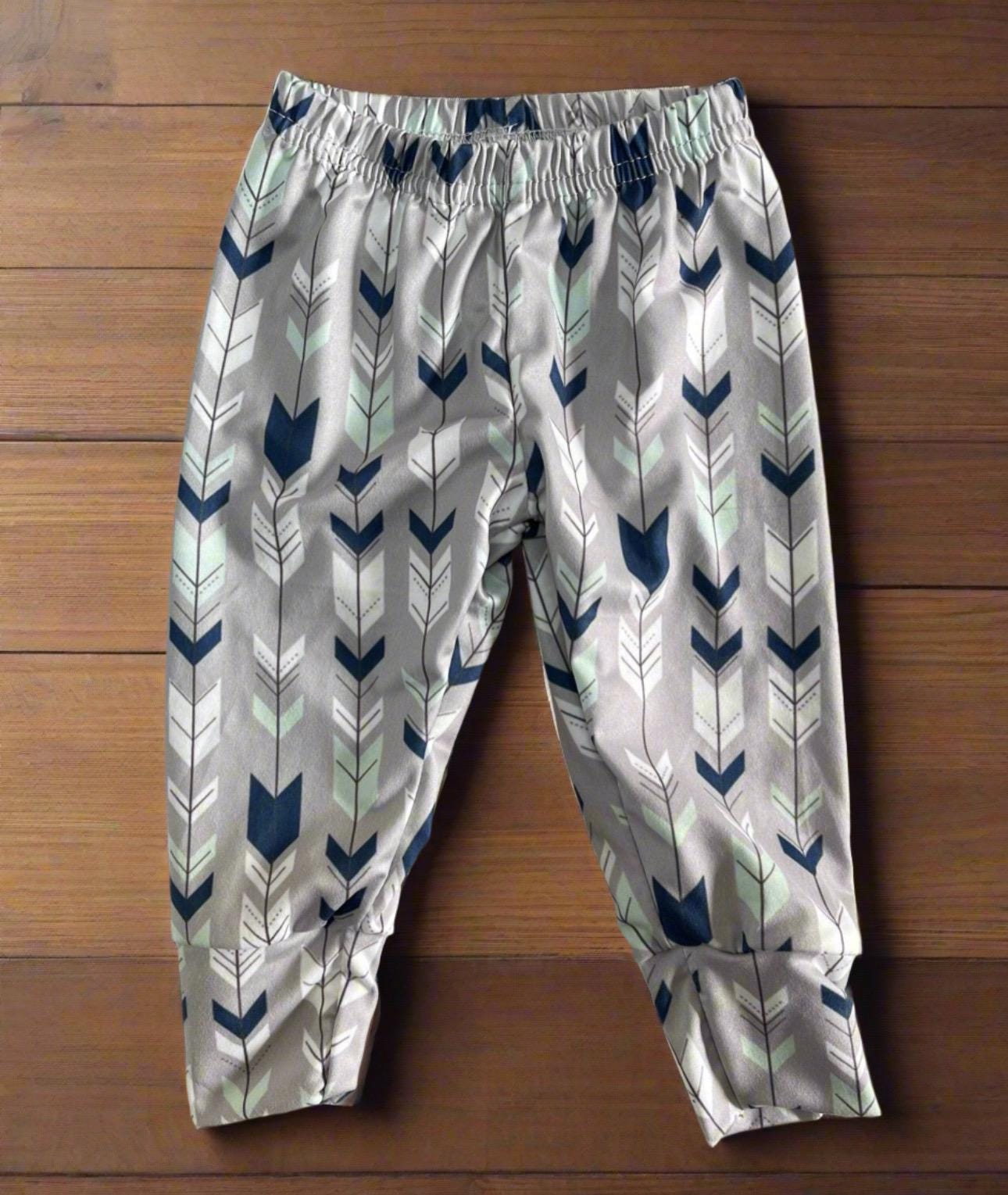 Wild One Jogger Set for Kids! Featuring a bold arrow print on the jogger pants in shades of grey, white, blue, and mint, this set is paired with a striking blue t-shirt that proudly displays &quot;WILD&quot; down the front. Ships FREE with $35+ purchase
