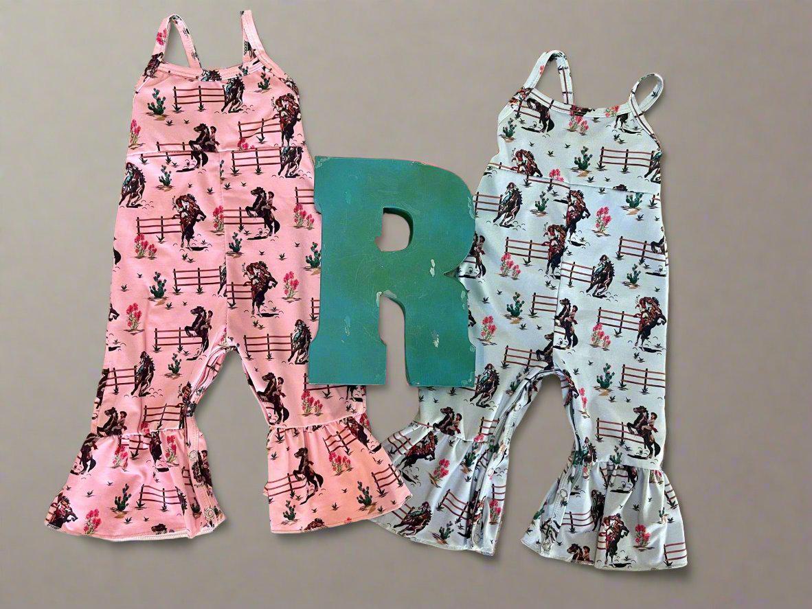 Razels Western Cowgirl Print Jumpsuit in Blue and pink. This fun jumpsuit features a vintage cowgirl print of bucking and rearing horses and their best cowgirls.  Legs have a flare/bell bottom hem and spaghetti strap. An easy-peasy outfit!