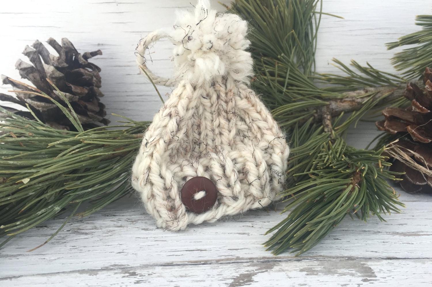 Handknit Mini Hat Christmas Tree Ornament. This hat is a white with black and brown flecks and a brown button centered on the brim. Hat also has an adorable, matching pom pom.