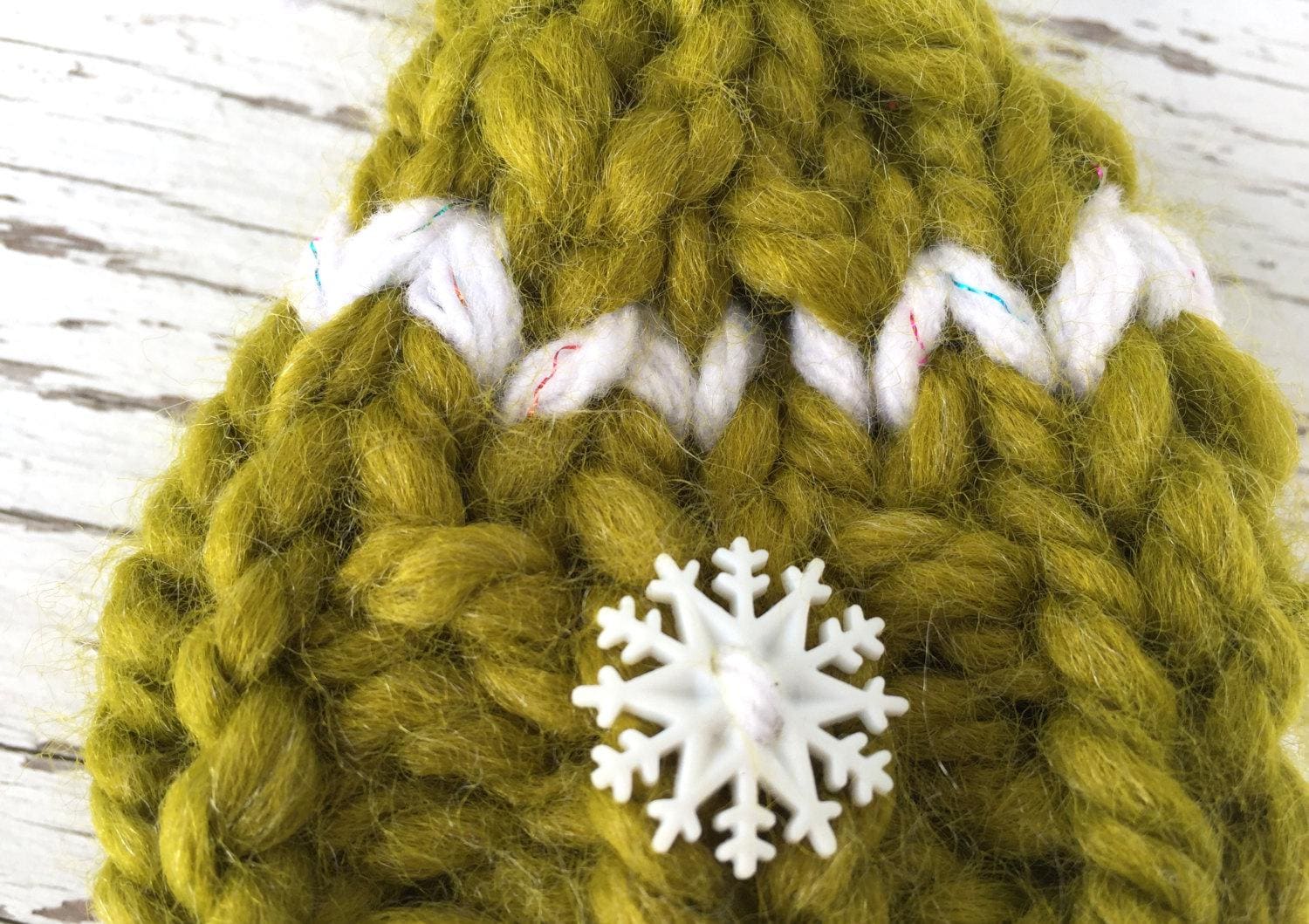 handknit green Christmas hat ornament with white snowflake button on brim, white detailing and a white and green pompom. Merry Christmas!