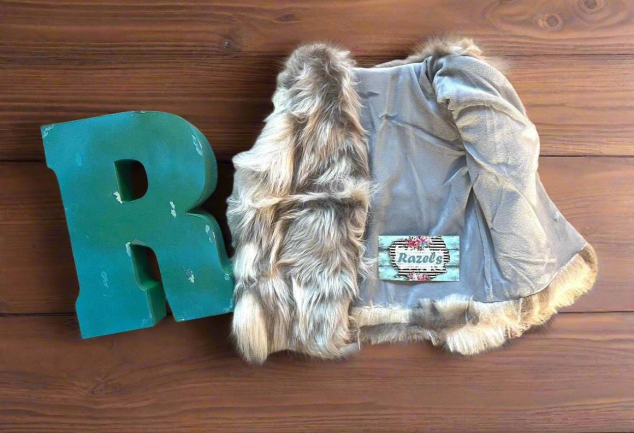 Cozy and stylish Kids&#39; Fur Vest in a blend of grey, black, brown, and cream. Perfect for layering over any outfit, this well-made vest keeps your child warm and photo-ready. The versatile colors make it easy to mix and match with her wardrobe.