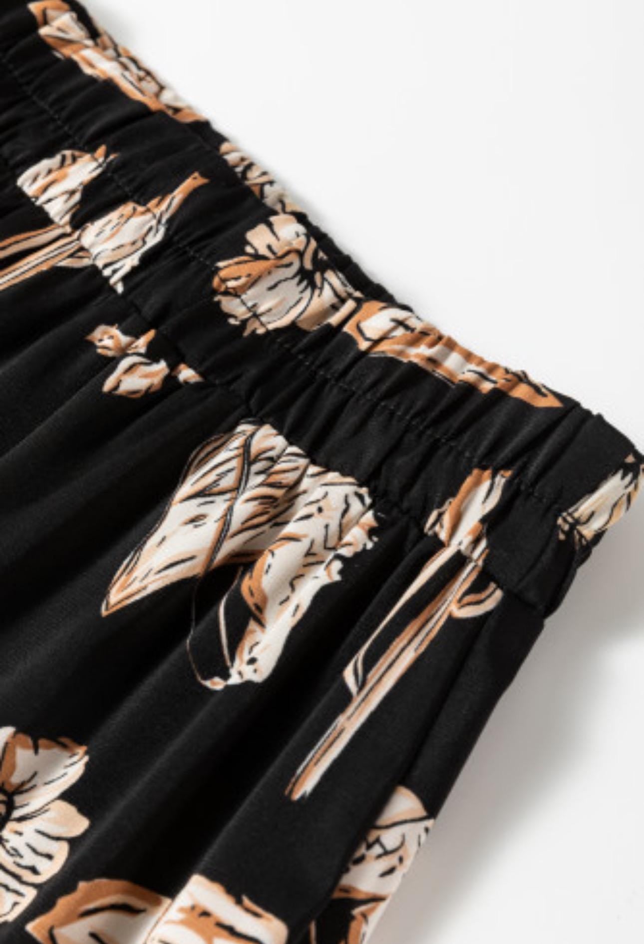 The Fall Women&#39;s Western BOHO maxi skirt features a charming western print with horses, cacti, flowers, and cowboy hats. It has a high-waisted design and a flowing silhouette in a fall color combo of black, brown, tan, and cream.