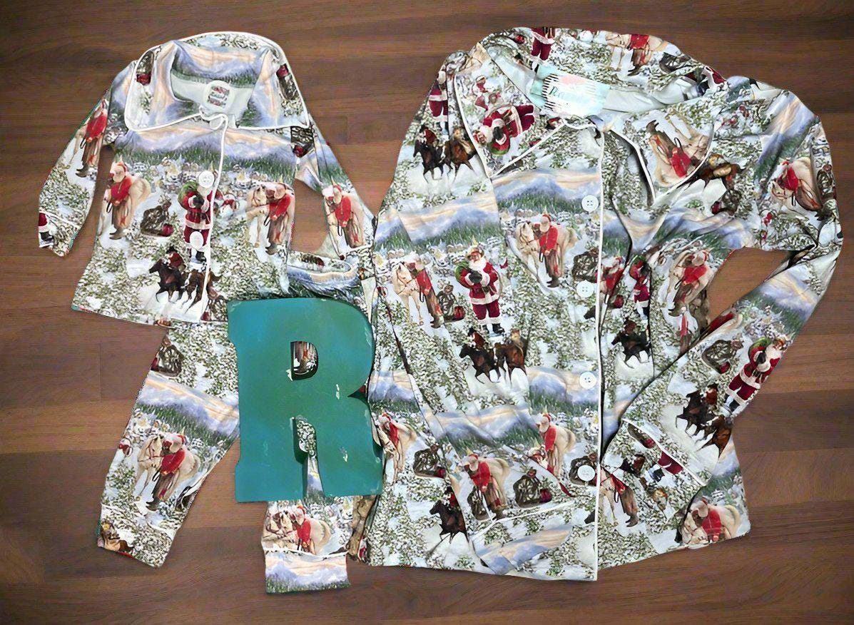 Cowboy Santa Christmas Pjs! These button-down Christmas pajamas feature a fun print of old Saint Nick himself with a few of his best horses! Cowboy Santa is leading one horse, riding a horse, delivering packages the Cowboy Way!