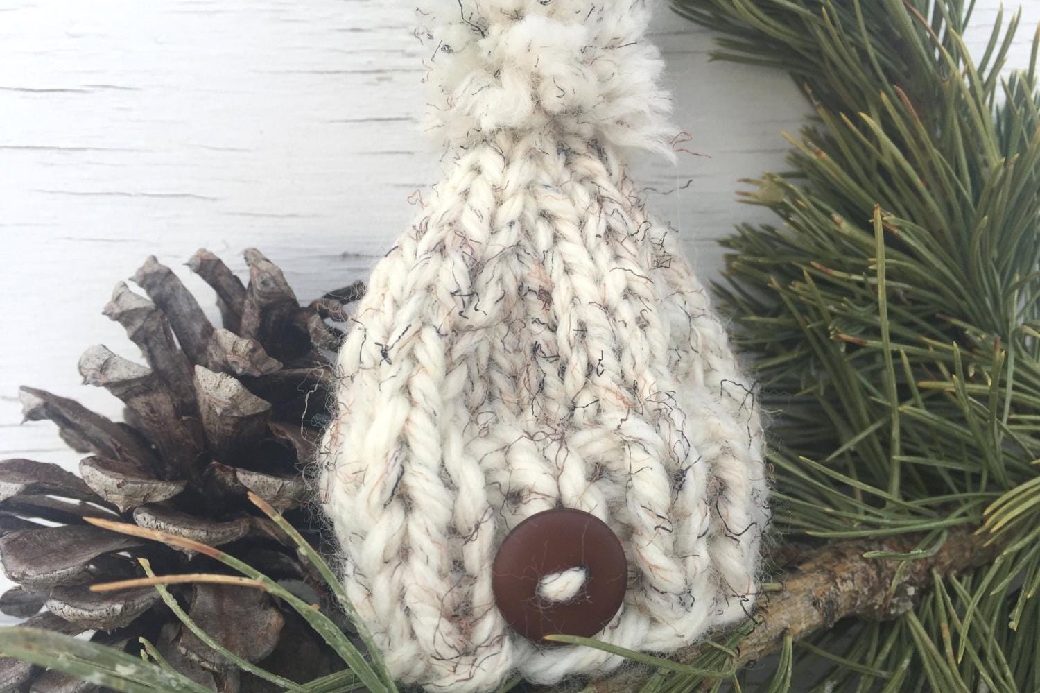 Handknit Mini Hat Christmas Tree Ornament. This hat is a white with black and brown flecks and a brown button centered on the brim. Hat also has an adorable, matching pom pom.