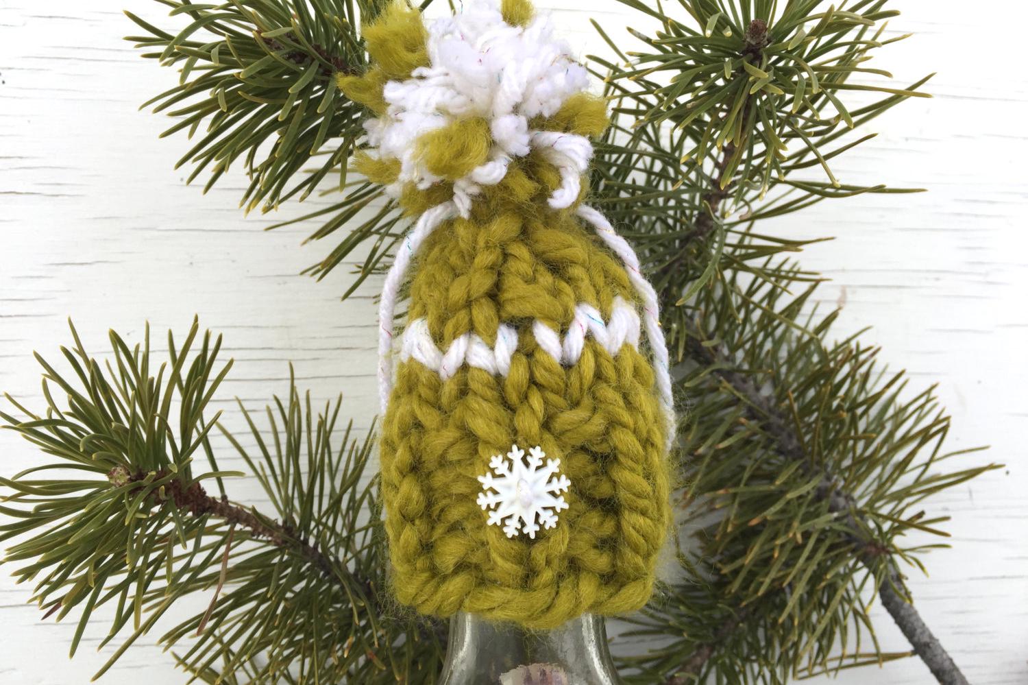 handknit green Christmas hat ornament with white snowflake button on brim, white detailing and a white and green pompom. Merry Christmas!