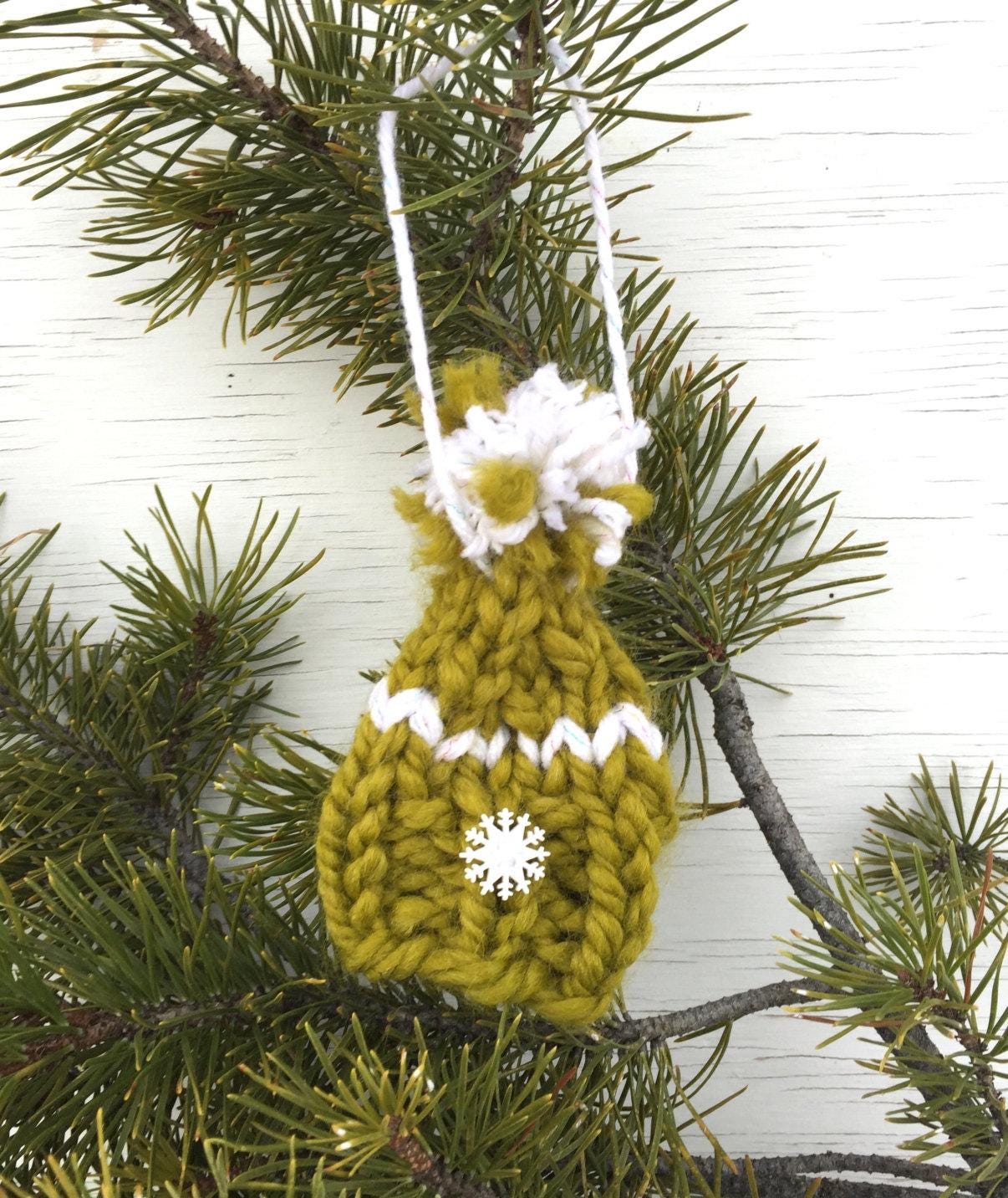 handknit green Christmas hat ornament with white snowflake button on brim, white detailing and a white and green pompom. Merry Christmas!