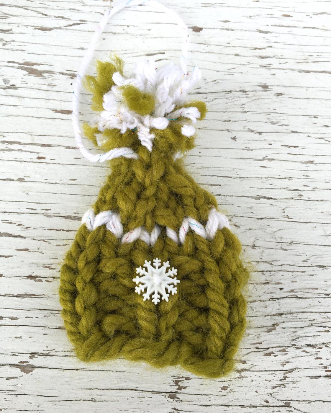 handknit green Christmas hat ornament with white snowflake button on brim, white detailing and a white and green pompom. Merry Christmas!