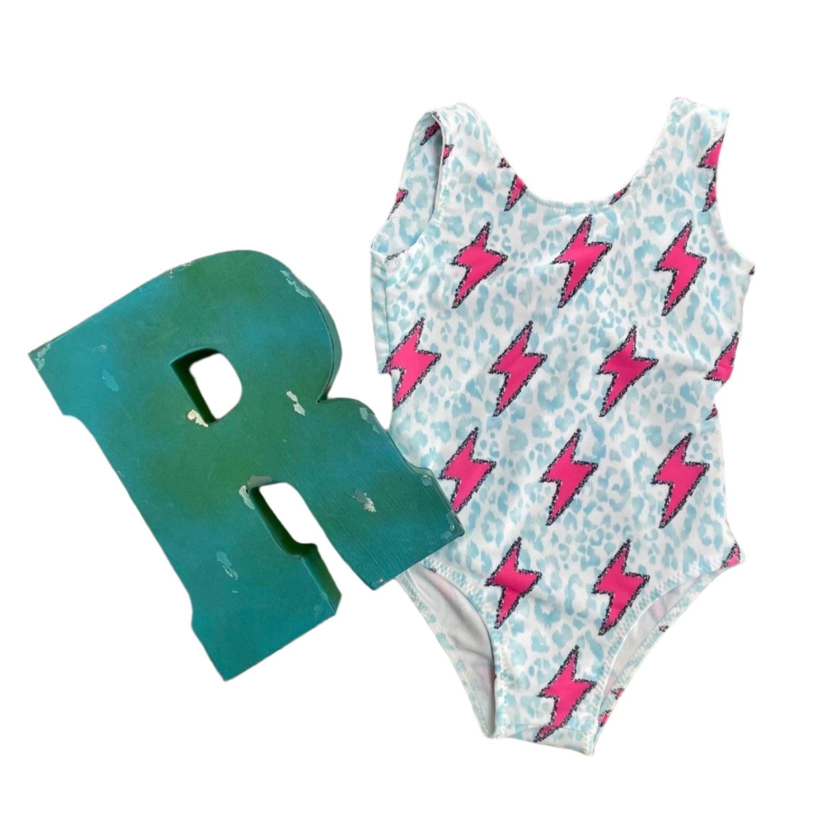 Pink Lightning Bolt One- piece Swimsuit is a Turquoise Cheetah Print One-Piece swimsuit featuring a striking pink lightning bolts and turquoise cheetah print design with a tie-back detail. Available in sizes 0/3 months to 8/9 years. Ships FREE $35+