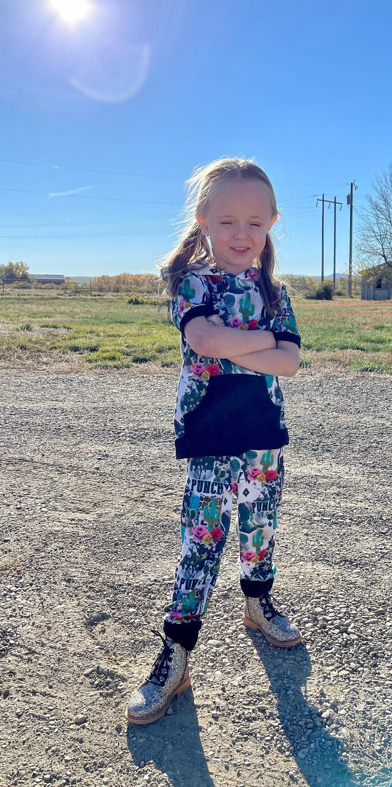 Girls Cowgirl Outfit | Western Hoodie Jogger Set for Kids  This Girls PUNCHY Cowgirl Outfit is full of retro cowboy vibes. This Western outfit features an allover Western print with matching jogger pants and a lightweight, short-sleeved hoodie top.