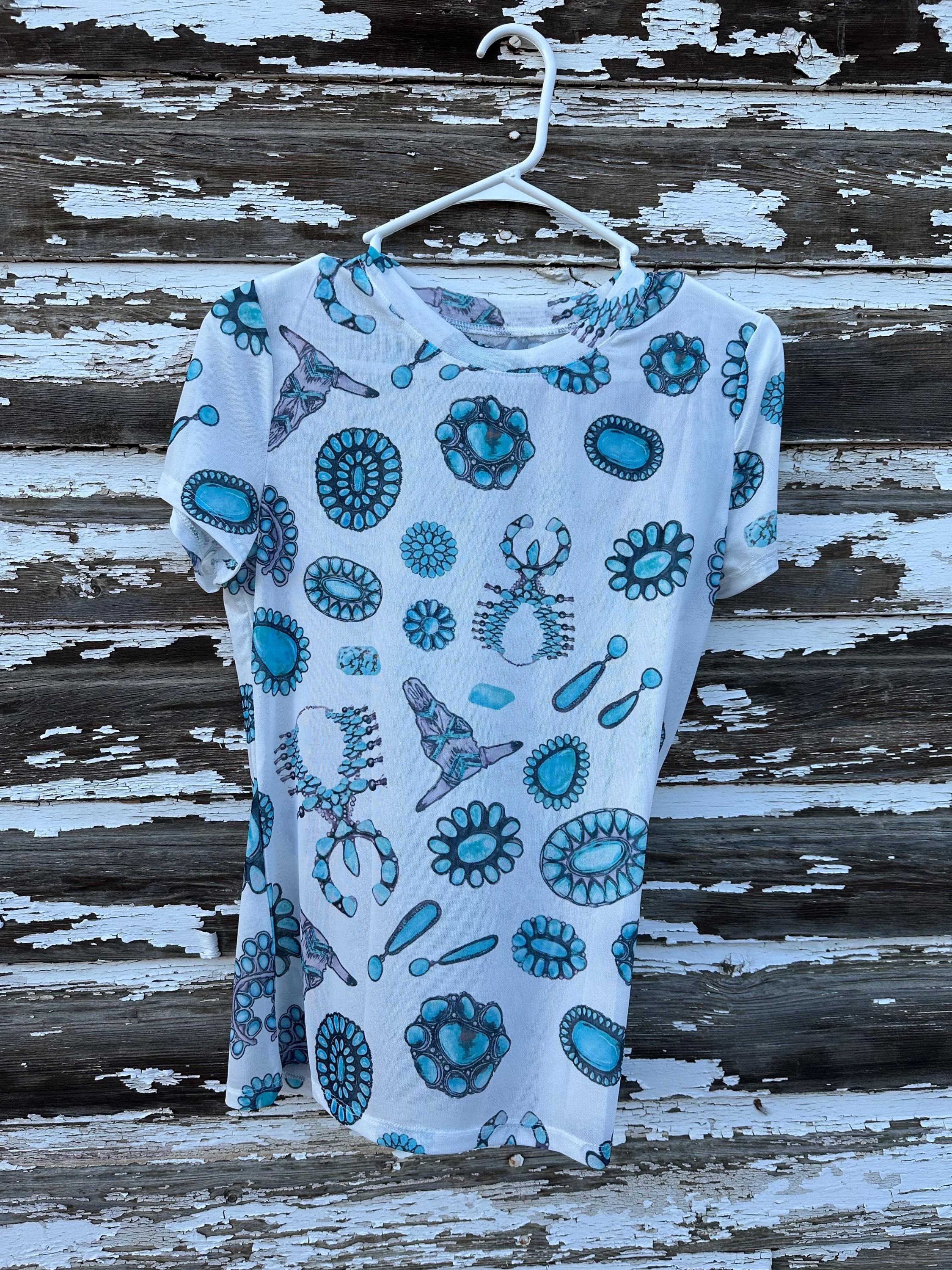 Add a touch of Western flair with this stylish Western Mesh  Shirt!  Talk about Cowgirl Aesthetic! Featuring cow skulls, squash blossoms, and turquoise conchos, this sheer print tee is soft, comfy, and perfect for layering....or not! Shop Razels—ships FREE with $35+ purchase from MONTANA TODAY!