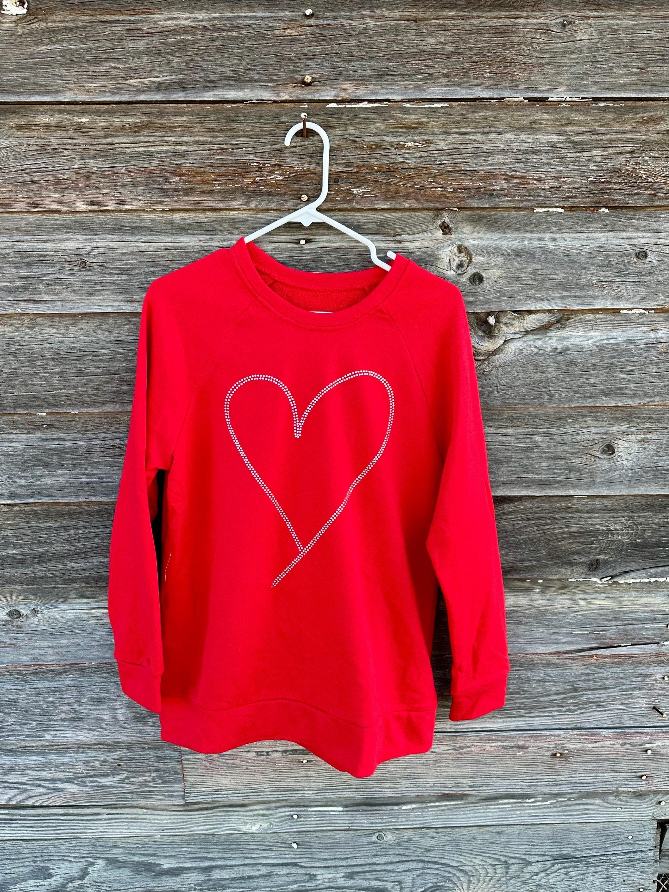 Add sparkle to your style with the Rhinestone Heart Shaped Sweatshirt! Featuring a glittering heart design, relaxed neckline, and cozy long sleeves, it&#39;s perfect for all-day comfort. Ships for FREE—shop Razels now!