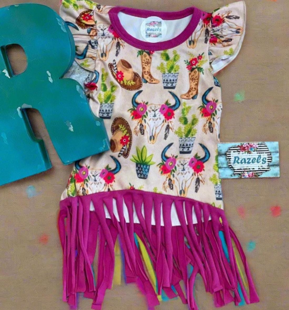 Cowgirl Fringe Dress – The Perfect Western Tunic for Little Cowgirls features a vibrant western print, flutter sleeves, a charming tie-back, and thick pink fringe. Let your little cowgirl shine in this Cowgirl Fringe Tunic Dress!