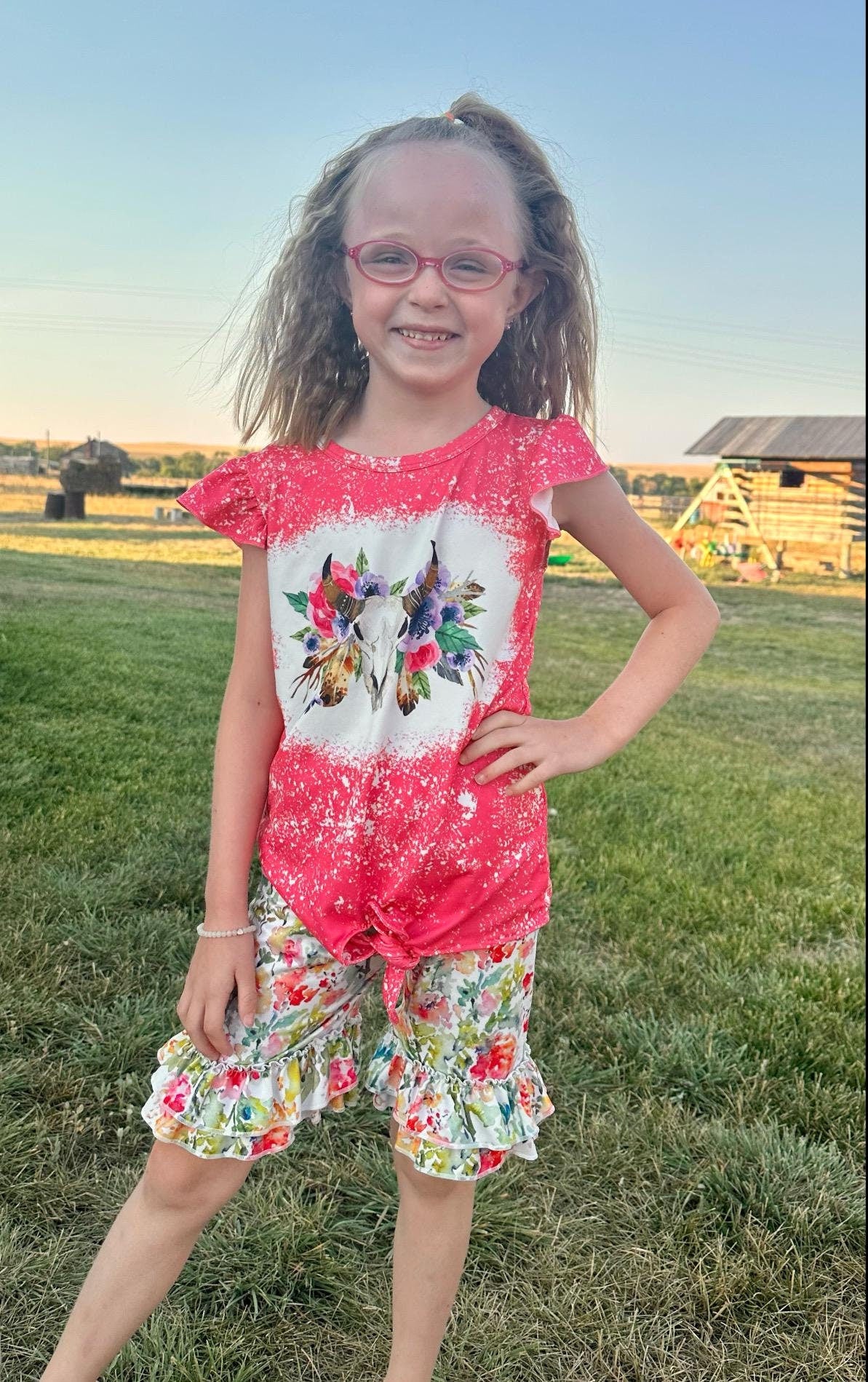 This Cowgirl BOHO Short Set is sweet, sassy, and full of Western charm — perfect for your little rodeo princess! The soft bleach-splattered ruffle sleeve tee features a bold cow skull with colorful flowers, a trendy tie-front hem, and boutique-quality detailing. Paired with matching ruffle shorts in a beautiful all-over floral print, this outfit is made for both style and play.
✓ Adorable Western boho design for girls, toddlers, and babies