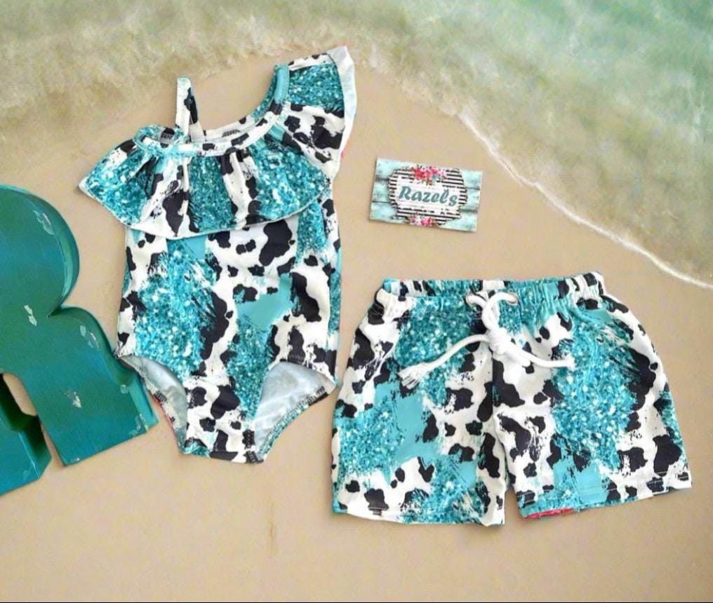 Turquoise Cowprint Matching Sibling Swimsuits – Western Swimwear for Kids

Make a splash in these adorable turquoise, black, and white cowprint swimsuits! Featuring a ruffled neckline on the one-piece and comfy unlined trunks, this matching set is perfect for little cowboys and cowgirls. Available in sizes 0-3 months to 8/9, these versatile swimsuits are designed for summer fun, whether at the pool, beach, or backyard adventures. Ships FREEwith $35+ purchase from MONTANA.