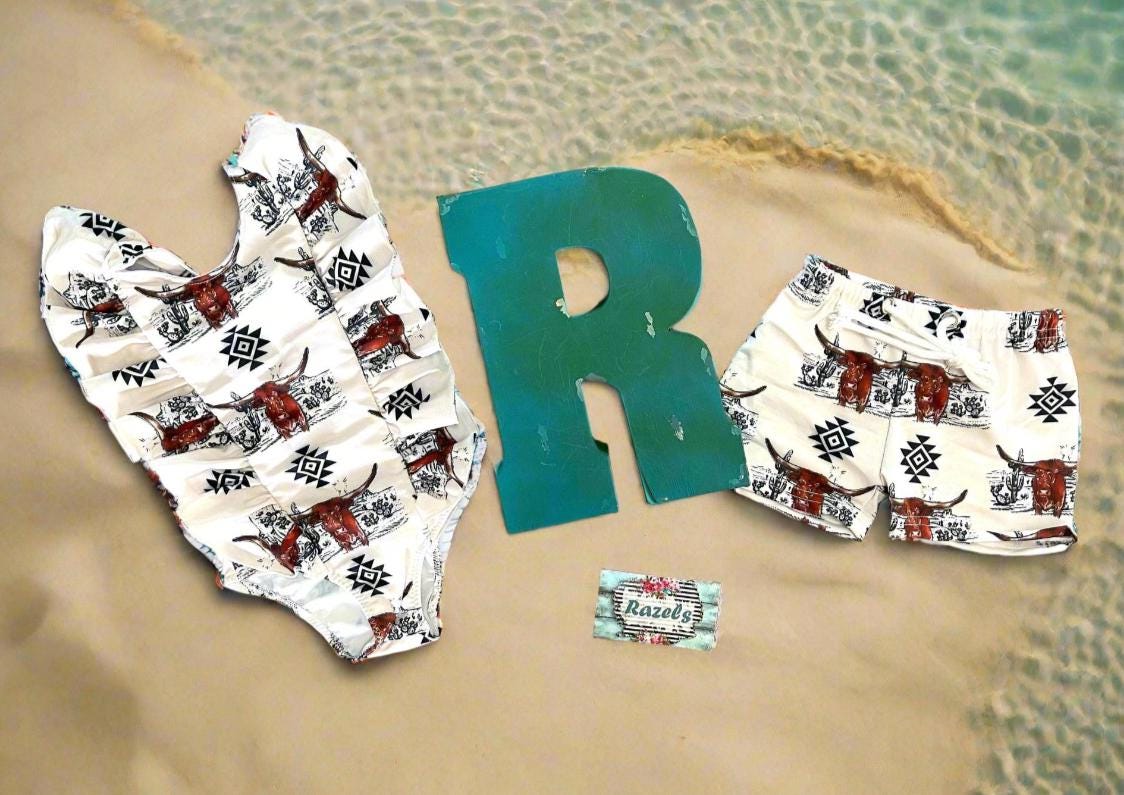 Western Swimsuits – Longhorn Steer Sibling Swimsuits. Get ready for summer with these Matching Swimsuits featuring a bold Longhorn Steer design! This black-and-white desert scene with a geometric touch is perfect for little cowboys and cowgirls who love Western style. 
 Cowboy Swim Trunks: Unlined for comfort, with a functional drawstring—also great as stylish day shorts!
Cowgirl Swimsuit: An adorable one-piece swimsuit with front ruffles fit for little rodeo queens!