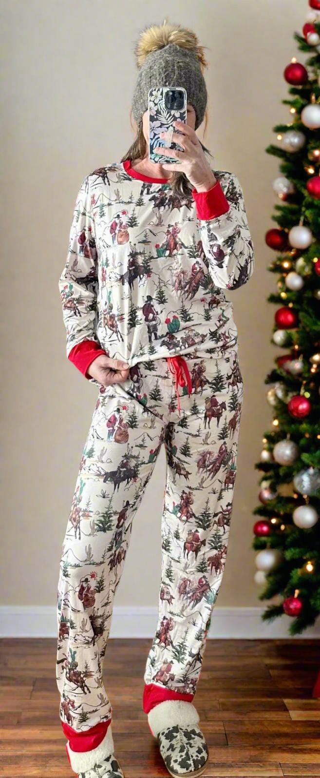 Cowboy Santa Christmas pajamas feature Cowboy Santa delivering packages on his trusty horse, riding among the trees and mountains. The cuffs of the long-sleeve top and pajama pants, as well as the neckline, are red.