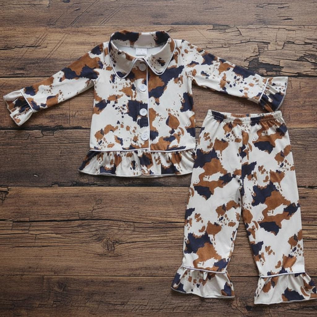 🐮 Cowprint Kids Pajamas – Western Ruffle Lounge Set | Fall & Christmas Gift Idea

Oh my stars — these Cowprint Pajamas are the cutest thing sin9ce cowboy boots on a baby! 🤎 Cozy, stretchy, and full of Western flair, this two-piece set is perfect for bedtime cuddles, fall photos, or Christmas morning with the family.
✓ Soft + stretchy for easy movement
✓ Button-front top with ruffle trim
✓ Matching ruffle-hem pants
✓ Cute brown + black cowprint on creamy background
