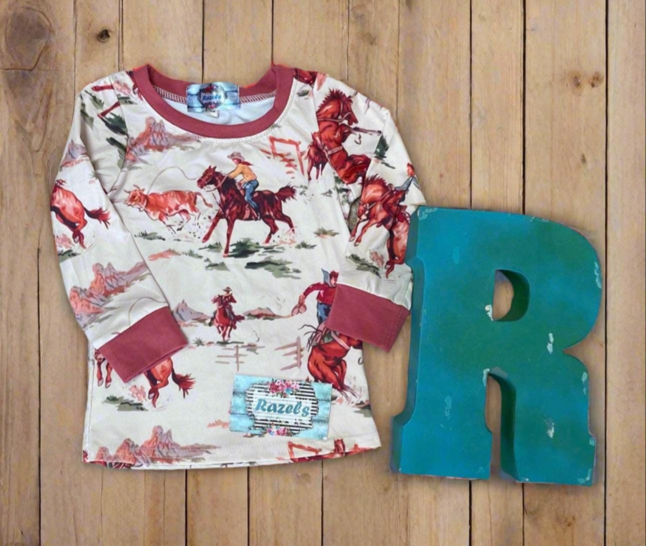 Kids Cowboy Pajamas are a Razels exclusive—featuring a vintage-style Western print with bucking broncos, roping cowboys, and rodeo action galore! 
✓ Vintage Rodeo-Inspired Print – broncs, lassos, and cowboy flair
✓ Super Soft Cotton-Spandex Blend – c