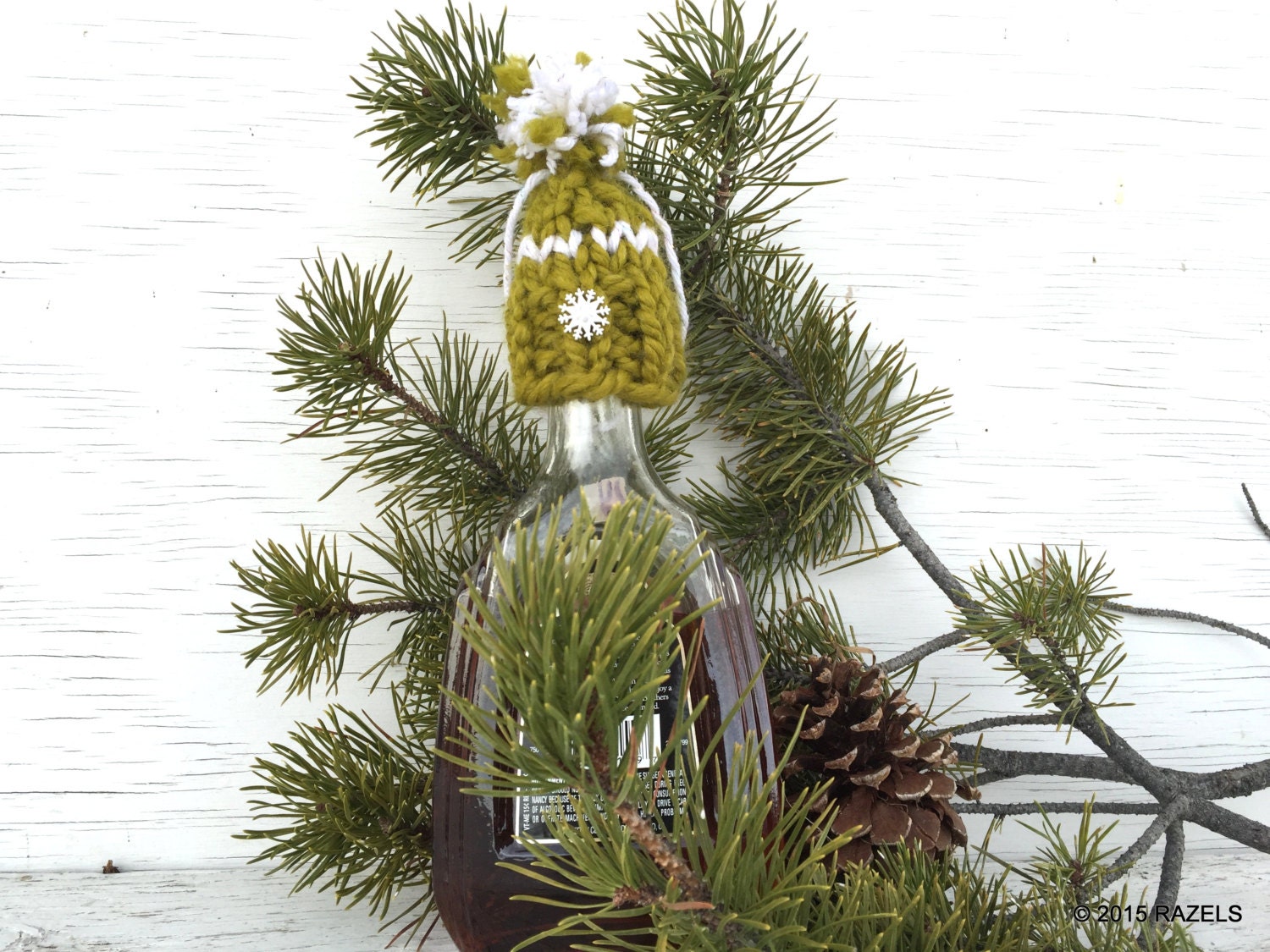 handknit green Christmas hat ornament with white snowflake button on brim, white detailing and a white and green pompom. Merry Christmas!