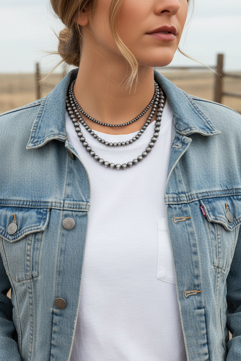Close-up of a woman wearing a layered necklace with a neutral background