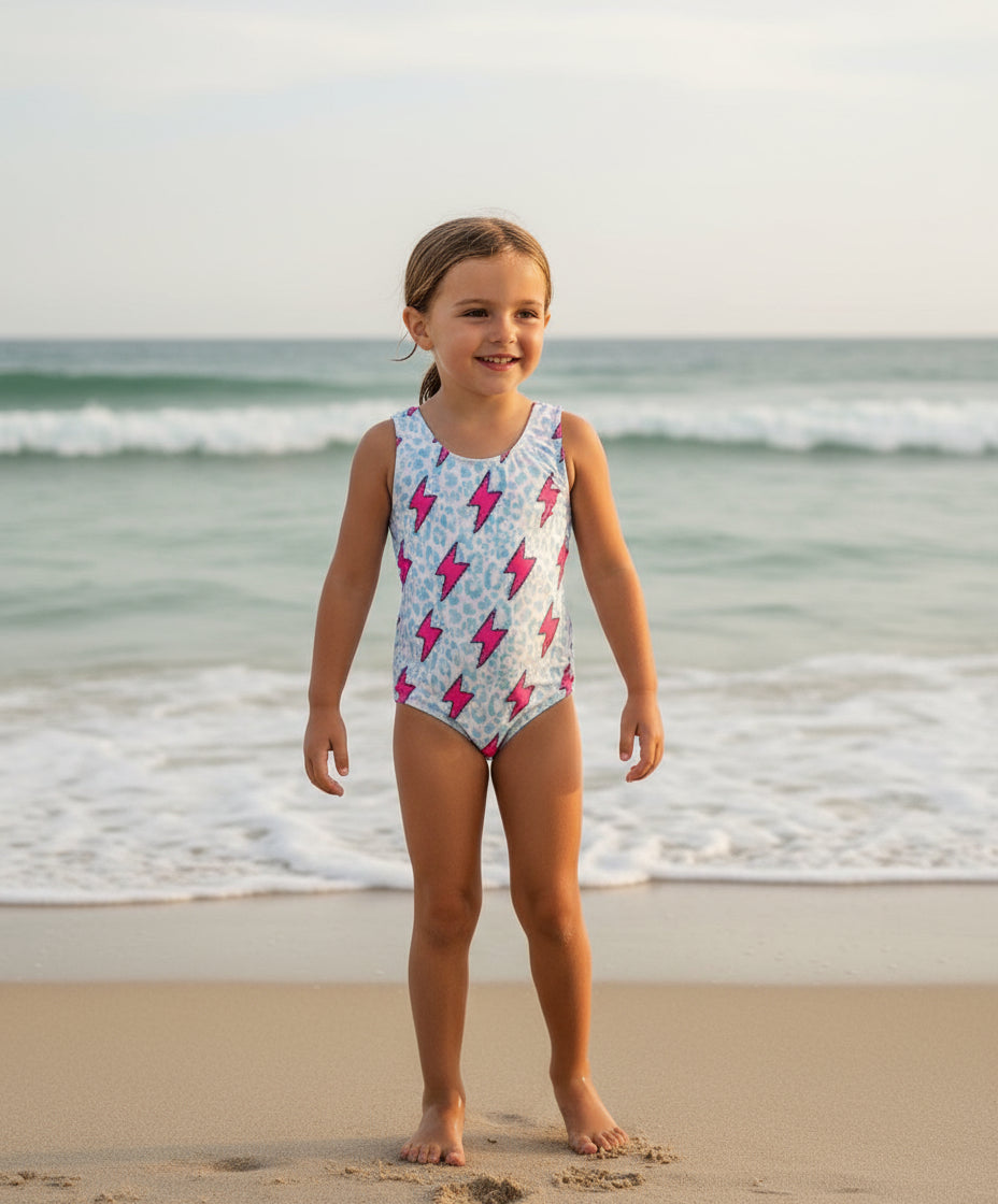 Pink Lightning Bolt One- piece Swimsuit is a Turquoise Cheetah Print One-Piece swimsuit featuring a striking pink lightning bolts and turquoise cheetah print design with a tie-back detail. Available in sizes 0/3 months to 8/9 years. Ships FREE $35+