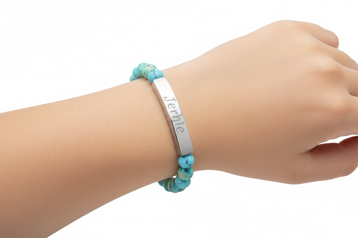 Turquoise beaded bracelet with a silver tag on a white background