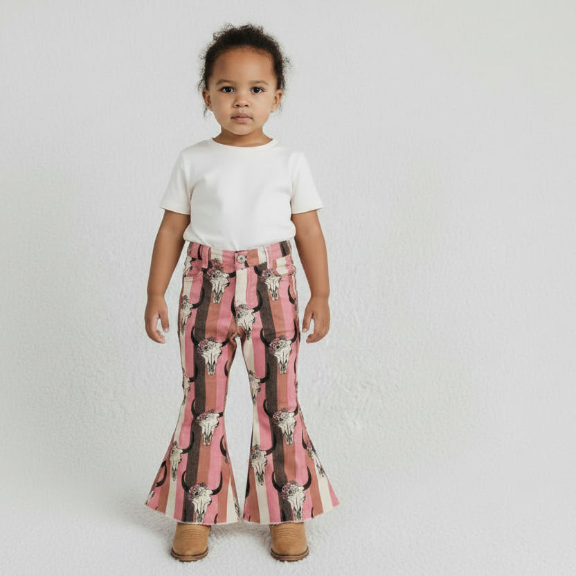 Child wearing a pink cowboy hat, white top, and plaid pants with cow pattern on a plain background
