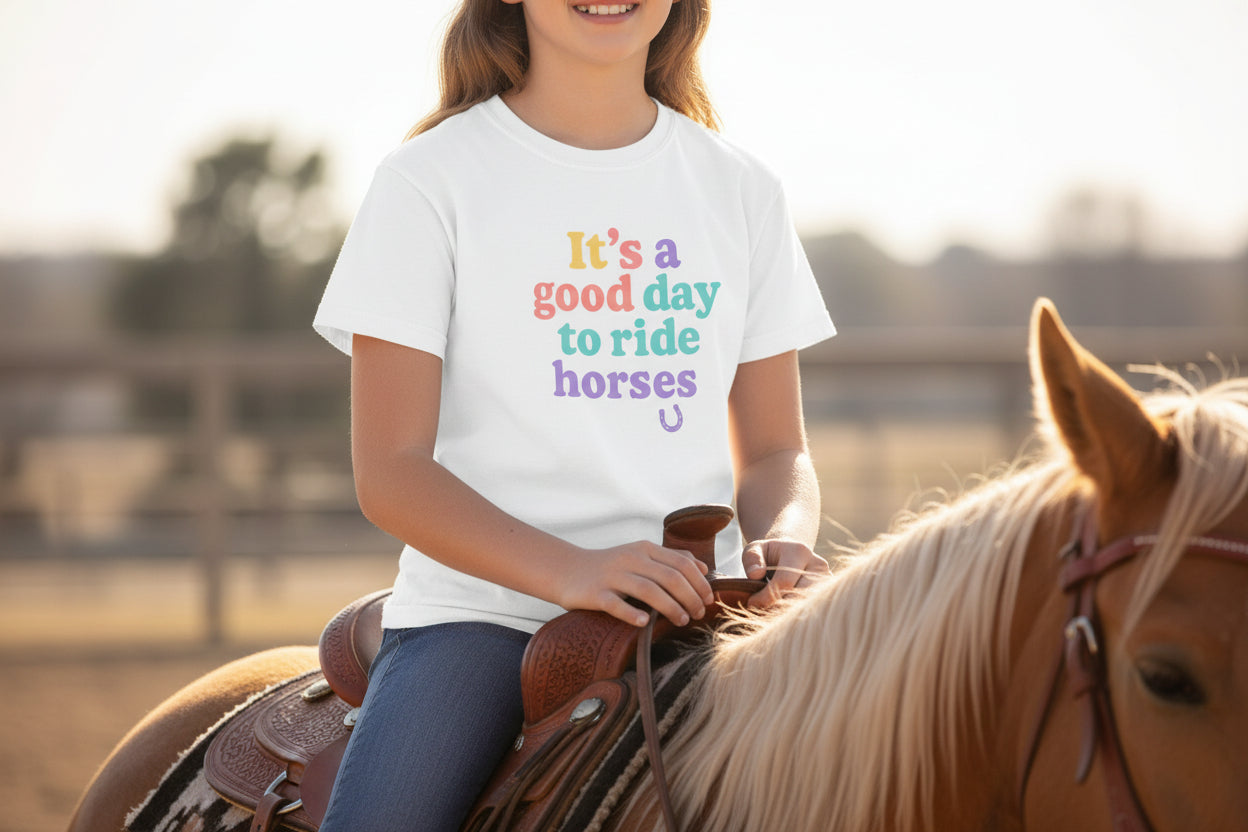 Child wearing a white t-shirt that says its a  good day to ride horses tshirt while riding a horse
