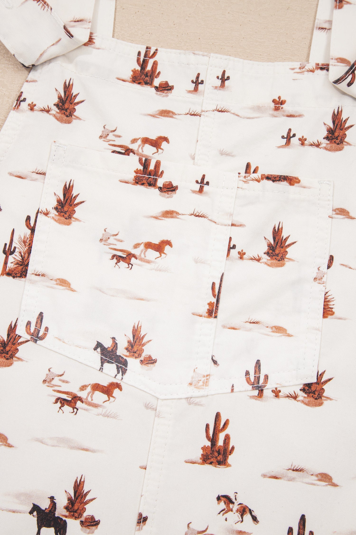 womens jumpsuit with desert landscape pattern featuring horses and cacti on a white background